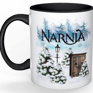 May include: White ceramic mug with a black rim and handle. The mug features a winter scene with snow-covered trees, a lamppost, and a small wooden door with the word "Narnia" written in a stylized font.