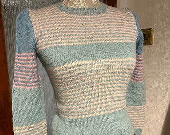 May include: A light blue and pink striped sweater with puffed sleeves. The sweater is knitted and has a crew neck.