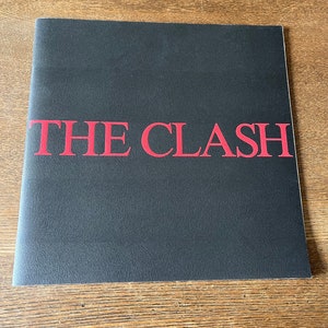 以下が含まれることがあります： 黒いビニールレコードのアルバムカバーで、赤い文字で「THE CLASH」と書かれています。