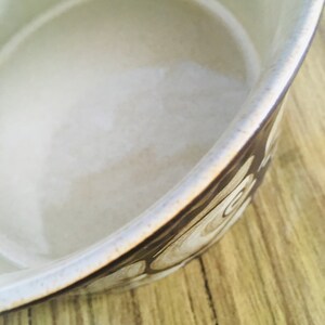 May include: A white ceramic bowl with a brown and white swirl pattern. The bowl is empty and has a smooth, glossy finish.