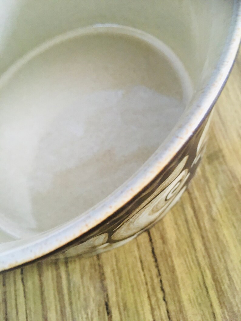 May include: A white ceramic bowl with a brown and white swirl pattern. The bowl is empty and has a smooth, glossy finish.