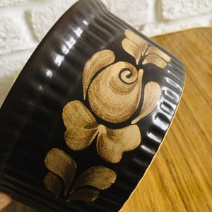 May include: A brown ceramic baking dish with a decorative floral design in a lighter brown color. The dish has a fluted rim.