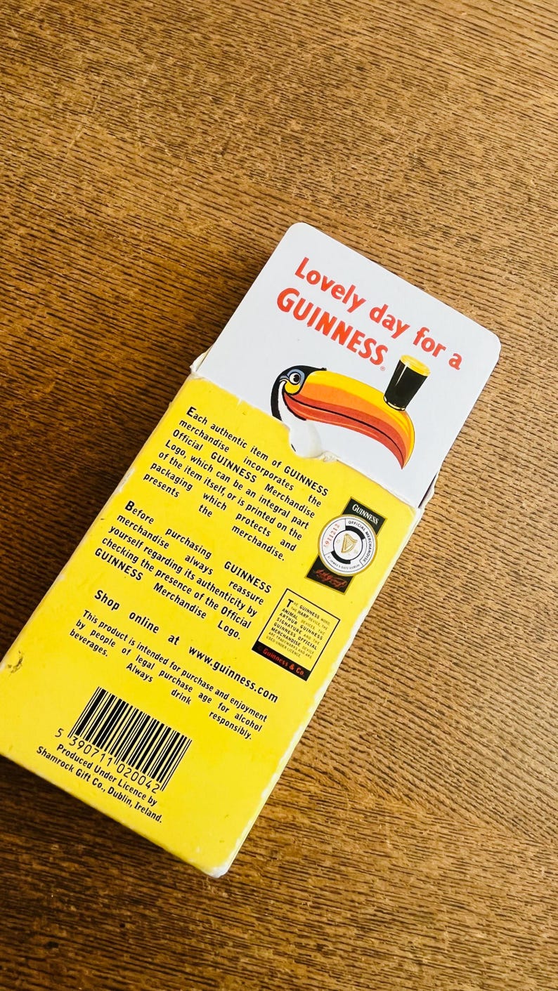 May include: A yellow and white GUINNESS merchandise box with the text "Lovely day for a GUINNESS". The box features a toucan illustration and product information. The box is intended for alcohol beverage enjoyment.