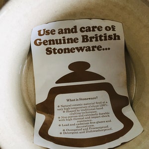 May include: A white card with brown text explaining the use and care of genuine British stoneware. The card features a brown illustration of a teapot. The text reads: "Use and care of Genuine British Stoneware... What is Stoneware? * Natural ceramic material fired at a very high temperature of about 1200&deg;c. * Shaped by traditional hand crafting techniques. * Non-porous and extremely durable with high thermal and impact shock resistance. * Lead and cadmium free glazes and decorations. * Ovenproof and Freezerproof. * Detergent and Dishwasherproof."