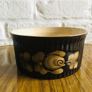 May include: A brown ceramic baking dish with a floral design in a lighter brown color. The dish has a fluted rim and is perfect for baking casseroles, desserts, or other dishes.