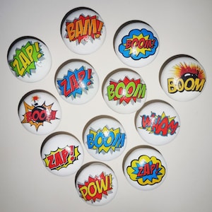 May include: Ten round white ceramic drawer knobs with colourful comic book sound effects like "BAM!" "POW!" "ZAP!" and "BOOM!" printed on them.