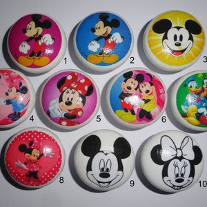 May include: Ten round white ceramic knobs with colourful Disney character designs. The designs include Mickey Mouse, Minnie Mouse, Donald Duck, and Goofy.