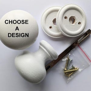 May include: White door knob set with a round knob and two round plates. The round knob has the text "CHOOSE A DESIGN" printed on it. The set includes screws.