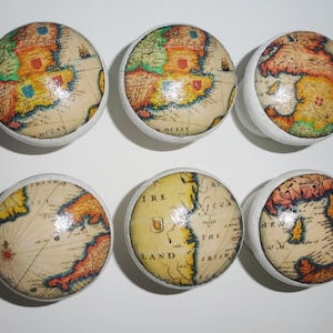 May include: Six round, white ceramic knobs with a vintage map design. Each knob features a different section of a map with a yellow, orange, green, and blue colour scheme. The maps are of the British Isles.