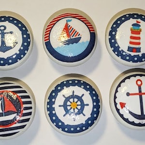 May include: Set of six nautical themed ceramic knobs with blue and white polka dots, stripes, and anchor designs. Each knob features a different nautical symbol, including a sailboat, lighthouse, and anchor.