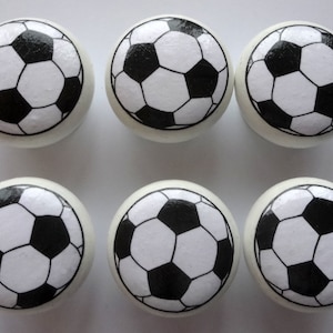 May include: Six white round knobs with black and white football designs.