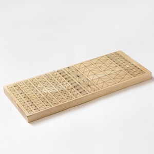 Könnte beinhalten: Ein Holzbrett mit einem geometrischen Muster, das in die Oberfläche geätzt ist. Das Muster besteht aus verschiedenen Formen, darunter Dreiecke, Quadrate und Rechtecke.