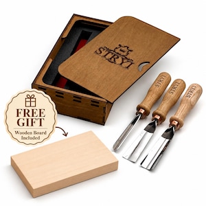 May include: A set of three wood carving chisels with light wood handles and metal blades, each branded with the text STRYI. The tools are accompanied by a rectangular wooden storage box with a sliding lid and a separate rectangular wooden board.
