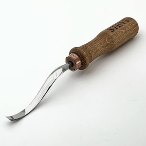 Puede incluir: Un cuchillo para tallar madera con una hoja curva de acero inoxidable. El mango es de madera marrón y tiene la palabra "STRYI" grabada. La hoja está unida al mango con una virola de cobre. Herramienta para trabajos de carpintería.