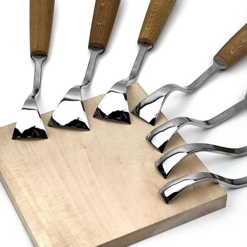 Peut inclure: Un ensemble de sept couteaux &agrave; palette en m&eacute;tal avec des manches en bois dispos&eacute;s en &eacute;ventail. Chaque outil pr&eacute;sente une lame en acier inoxydable poli et r&eacute;fl&eacute;chissant avec un col inclin&eacute;, variant en largeur et en courbure pour la peinture.