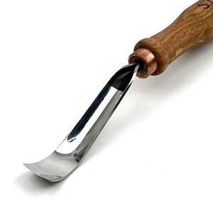 May include: A woodworking gouge with a curved, polished steel blade and a wooden handle. The blade is designed for carving and shaping wood. The handle is a light brown color and is attached to the blade with a copper ferrule.