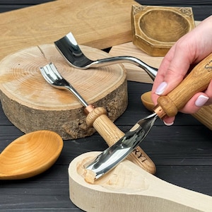 May include: A set of metal wood carving gouges with light brown wooden handles and copper-colored ferrules. The tools feature curved, polished steel blades designed for shaping wood, with one gouge currently carving into a light-colored wooden spoon.