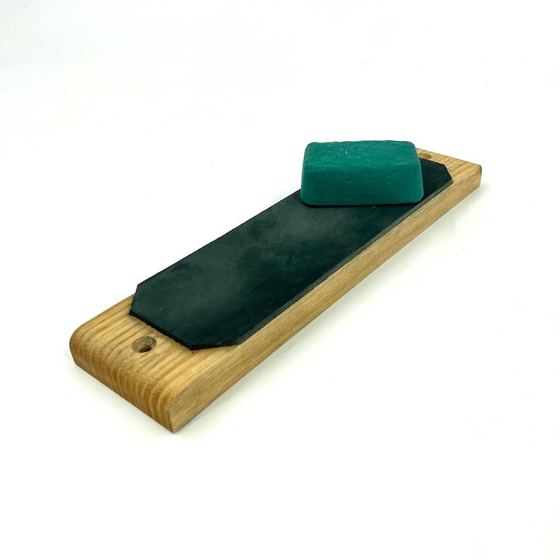 May include: A wooden strop with a black leather strop and a green polishing compound.