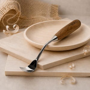 May include: A wood carving hook knife with a curved, polished metal blade and a smooth, light brown wooden handle. The handle features the brand name STRYI engraved in black lettering. The tool is designed for hollowing out wooden shapes.