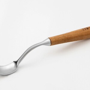 以下が含まれることがあります： 曲がったステンレス鋼の刃と木製の柄が付いたスプーン彫刻ツール。「STRYI」の文字が刻印されています。木工や彫刻プロジェクト向けに設計されています。