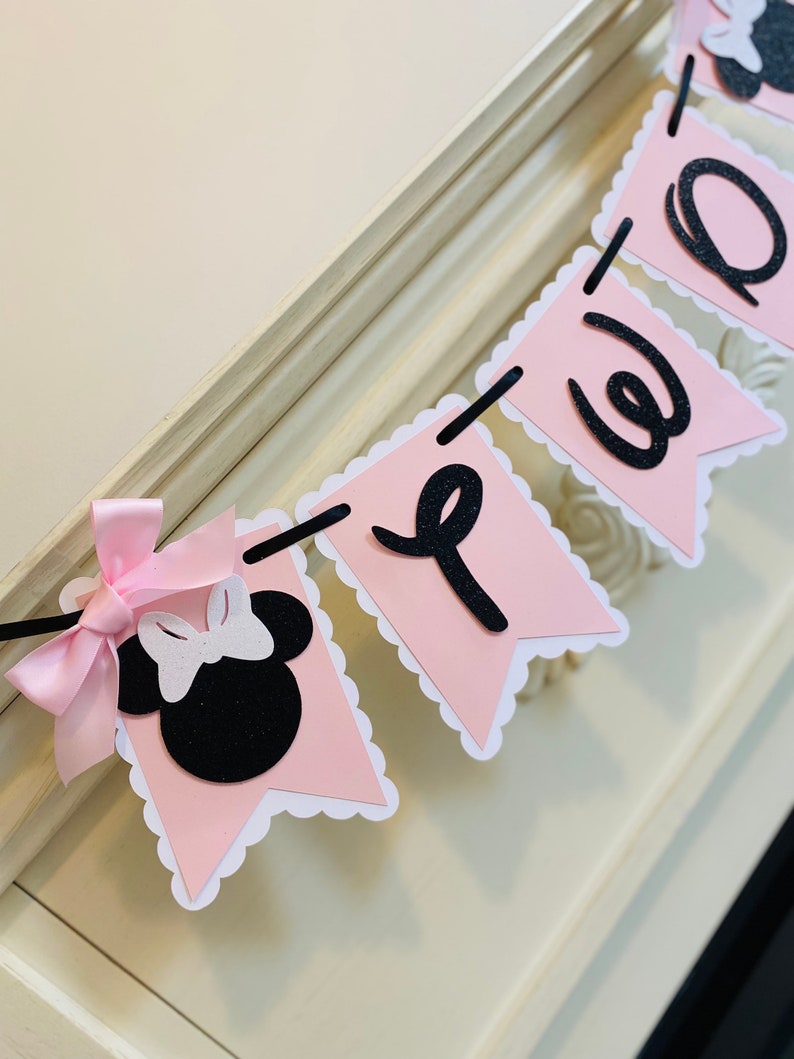 May include: Pink and black banner with the word "Welcome" in black letters. The banner has a scalloped edge and features a black and white Minnie Mouse head with a pink bow.