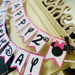 May include: Pink and black Minnie Mouse themed birthday banner with the words "Happy 2nd Birthday".