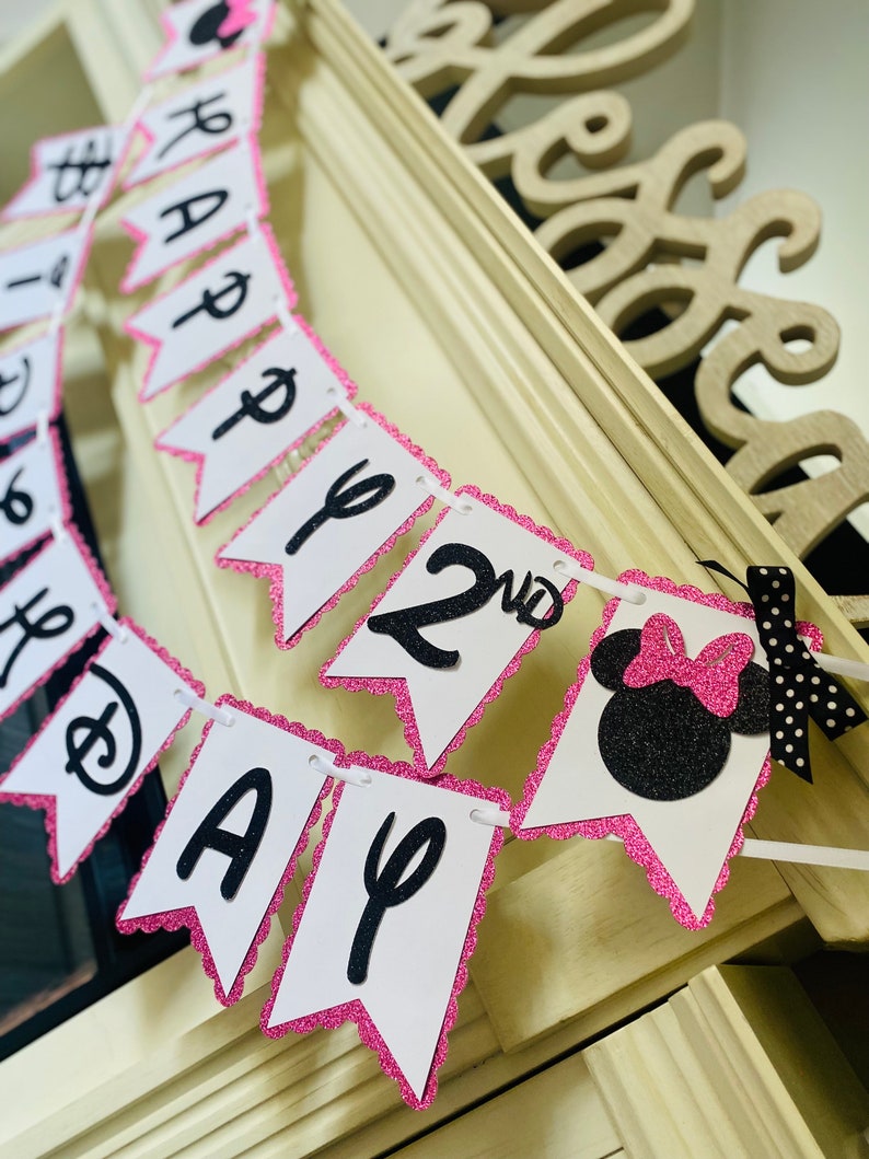 May include: Pink and black Minnie Mouse themed birthday banner with the words "Happy 2nd Birthday".