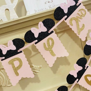 May include: Pink and black Minnie Mouse themed banner with gold glitter letters spelling out "Happy 2nd".