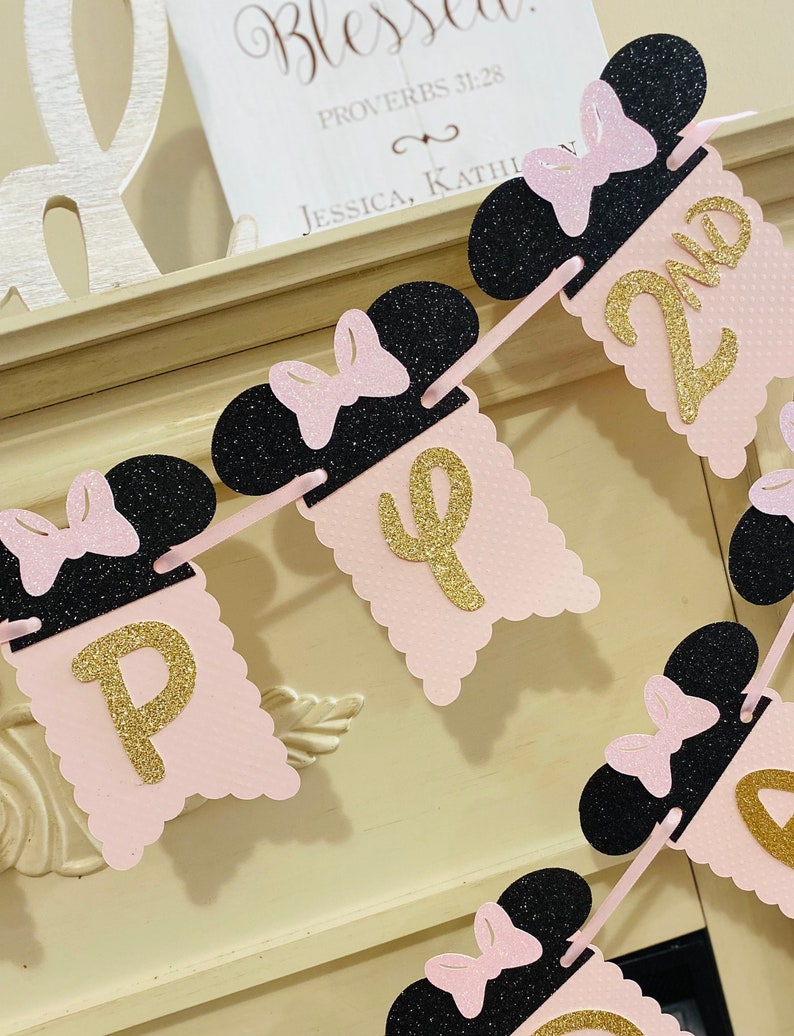 May include: Pink and black Minnie Mouse themed banner with gold glitter letters spelling out "Happy 2nd".