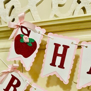 May include: A red glitter apple with a pink bow and a green leaf, a white banner with pink scalloped edges and red glitter letters spelling "Happy"