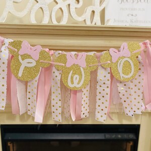 May include: A gold glitter banner with pink bows and the letters "Y", "O", "W", and "O". The banner has pink and white polka dot fabric and pink ribbons hanging from it. The word "Blessed" is above the banner.