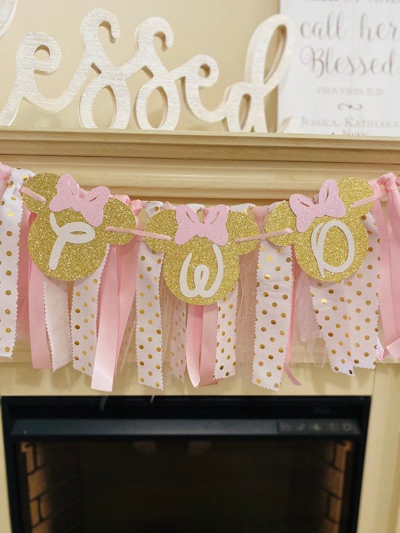 May include: A gold glitter banner with pink bows and the letters "Y", "O", "W", and "O". The banner has pink and white polka dot fabric and pink ribbons hanging from it. The word "Blessed" is above the banner.
