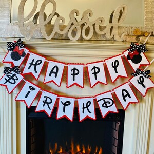 May include: A white and red banner with black letters that reads "Happy Birthday". The banner is decorated with black and red Minnie Mouse heads.