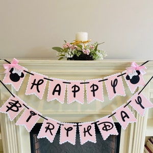 May include: Pink and black Happy Birthday banner with Minnie Mouse ears on each end. The banner is strung on a black string and has a scalloped edge.