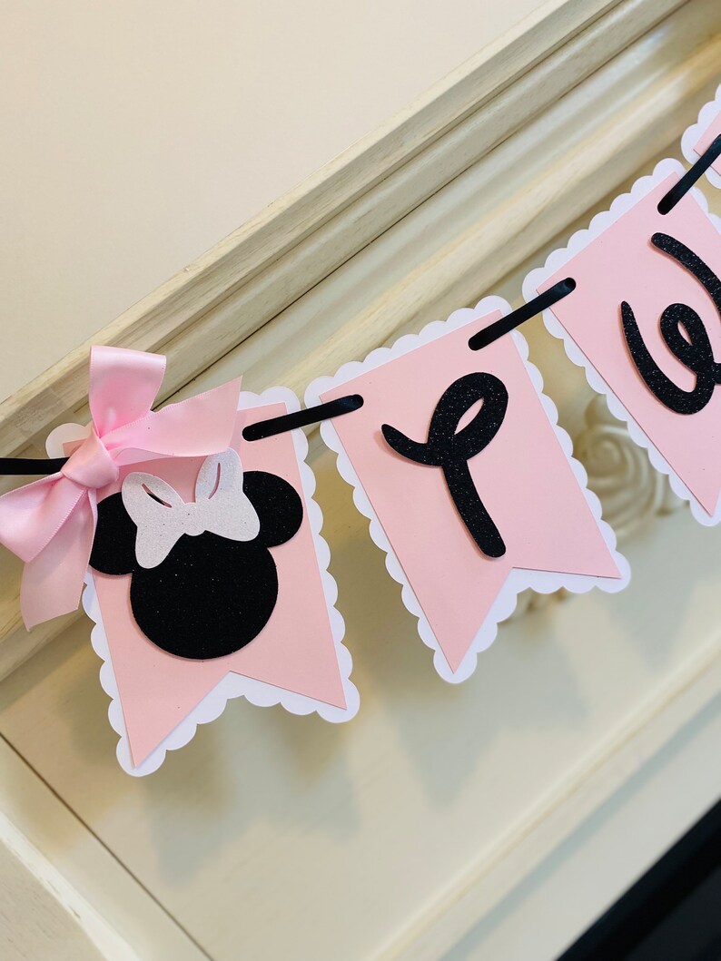 May include: Pink and black banner with scalloped edges. The banner says "Welcome" and features a black and white Minnie Mouse head with a pink bow.