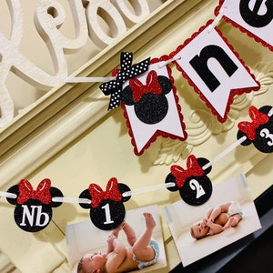 May include: A red and black Minnie Mouse themed first birthday banner with black glitter numbers and red bows. The banner includes photos of a baby at different ages.