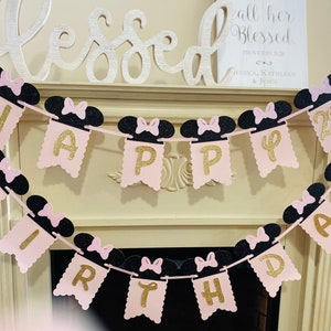 May include: Pink and black Happy 2nd Birthday banner with Minnie Mouse ears. The banner is made of glitter cardstock and has gold letters.