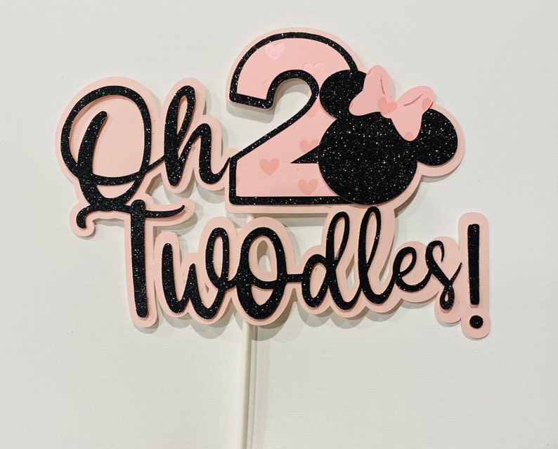 May include: Pink and black glitter cake topper with the text "Oh Twoodles!" and a number 2 with a pink Minnie Mouse head.