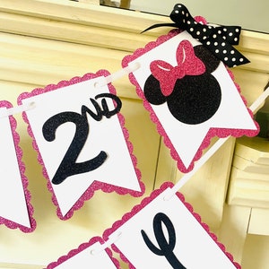May include: Pink and black glitter banner with the words "2nd" and "Birthday" in black letters. The banner also features a black and pink Minnie Mouse head with a pink bow.
