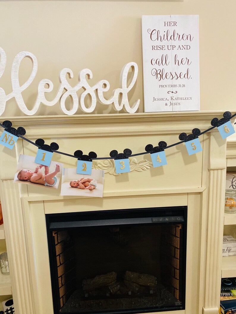 Pode incluir: Uma placa de madeira branca com o texto "Her Children Rise Up And Call Her Blessed." O texto est&aacute; em letras marrons com um toque de brilho dourado. A placa tamb&eacute;m inclui o texto "Proverbs 31:28" e "Jessica, Kathleen & Jesus".