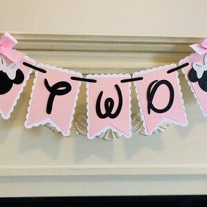 May include: Pink and black banner with the word "TWO" in black script letters. The banner is decorated with two black and white Minnie Mouse heads with pink bows.