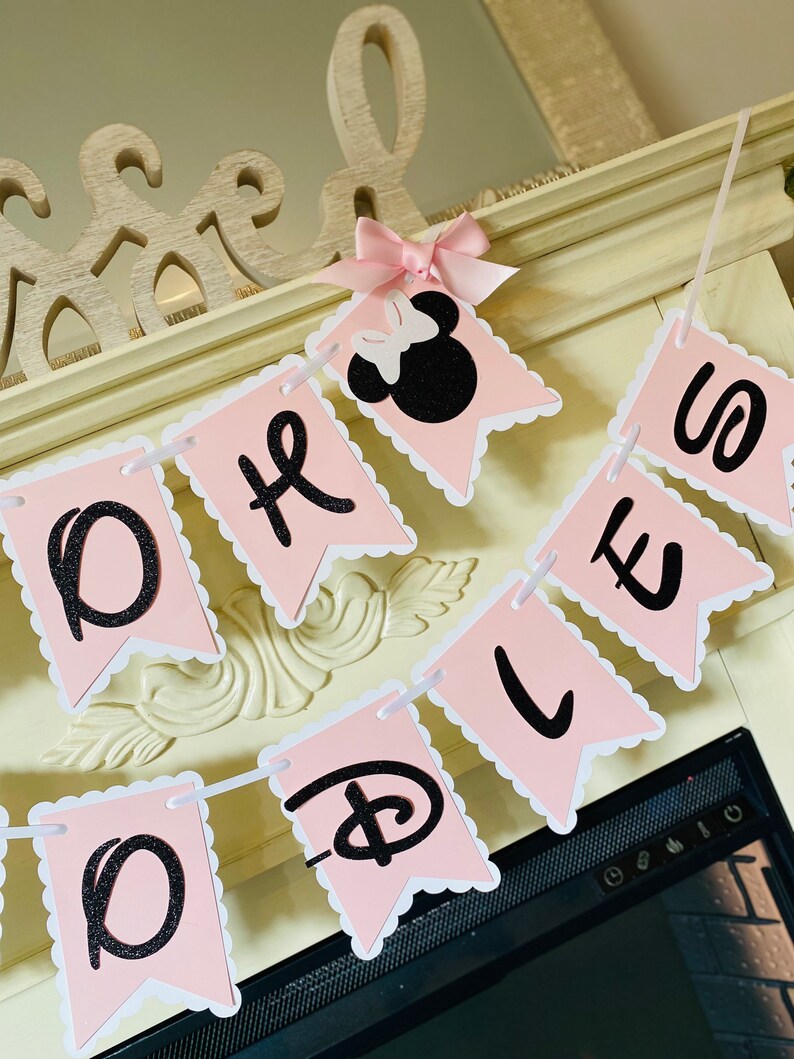 May include: Pink and black banner with the words "Oh Boy" and a Disney Mickey Mouse head with a pink bow. The banner is strung together with white string.