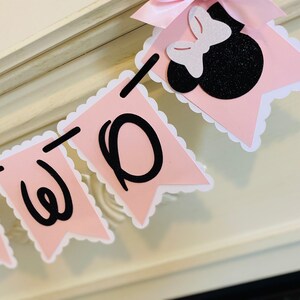 May include: Pink and white banner with black letters spelling "TWO" and a black and white Minnie Mouse head with a pink bow.