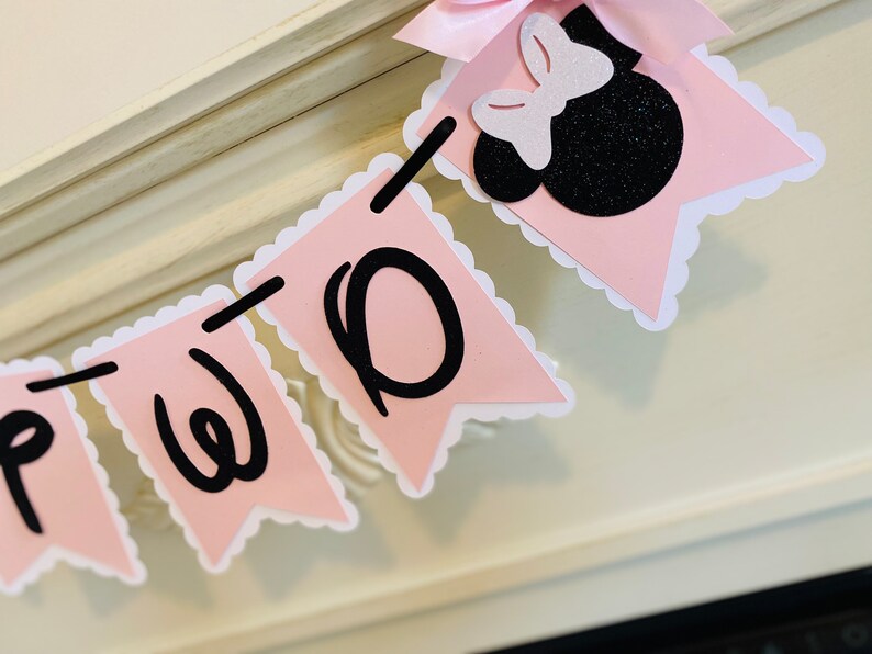 May include: Pink and white banner with black letters spelling "TWO" and a black and white Minnie Mouse head with a pink bow.