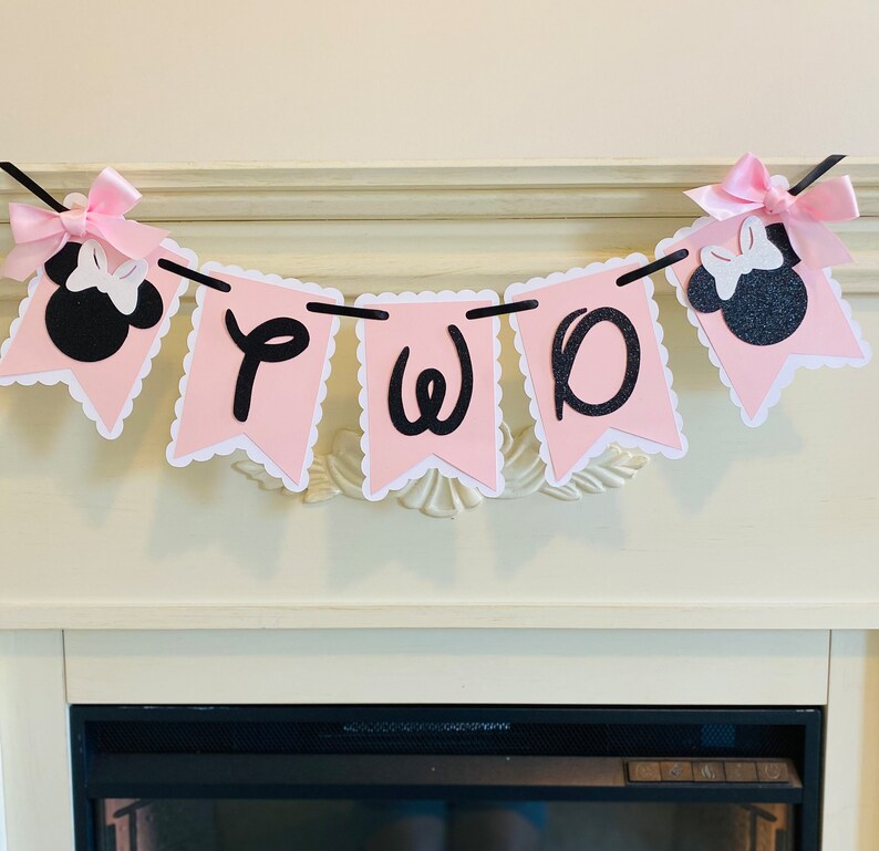 May include: Pink and black banner with the word "TWO" in black letters and two black Minnie Mouse heads with pink bows on each end.