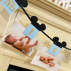 Pode incluir: Uma faixa tem&aacute;tica do Mickey Mouse em preto e dourado com cart&otilde;es azuis e brancos com os n&uacute;meros 1 e 9. A faixa &eacute; decorada com orelhas do Mickey Mouse pretas com glitter.