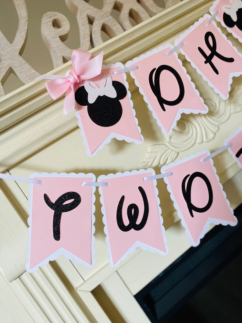 May include: Pink and black banner with the words "Two" and a black silhouette of Minnie Mouse with a pink bow.