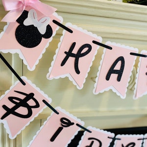 Puede incluir: Pancarta de Feliz Cumplea&ntilde;os rosa y negra con una cabeza de Minnie Mouse de purpurina negra al principio de la pancarta.