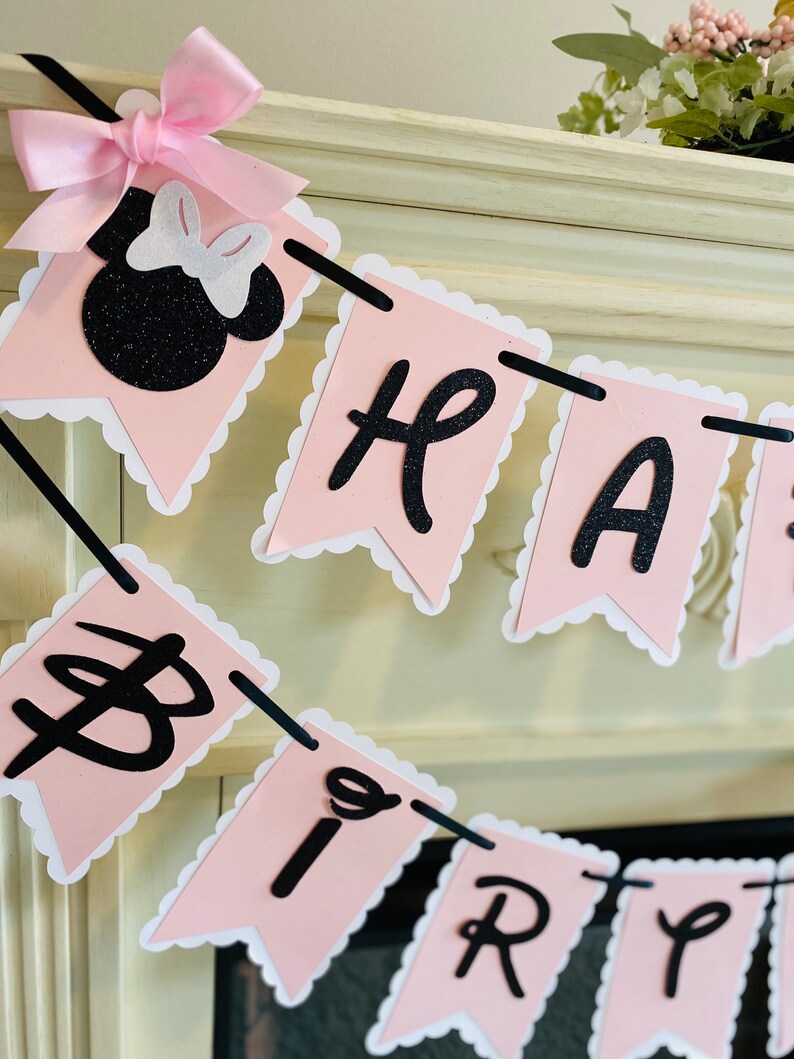 Puede incluir: Pancarta de Feliz Cumplea&ntilde;os rosa y negra con una cabeza de Minnie Mouse de purpurina negra al principio de la pancarta.