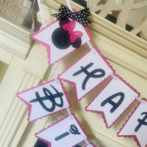 May include: Pink and white banner with black letters spelling "Happy Birthday" with a pink and black Minnie Mouse head at the top.